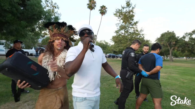 Akon singing during a live-streamed arrest of an alleged child predator, with YouTuber Vitaly and police officers in the background.