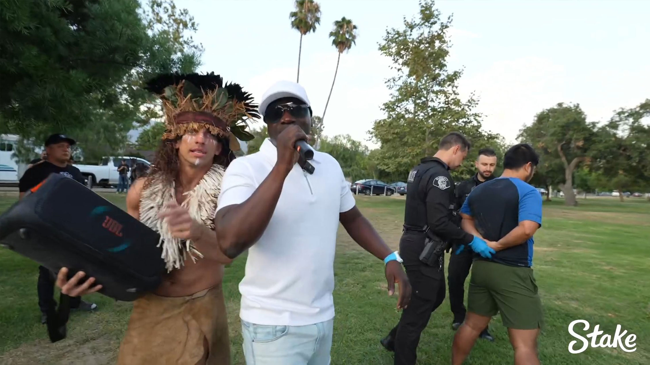 Akon singing during a live-streamed arrest of an alleged child predator, with YouTuber Vitaly and police officers in the background.