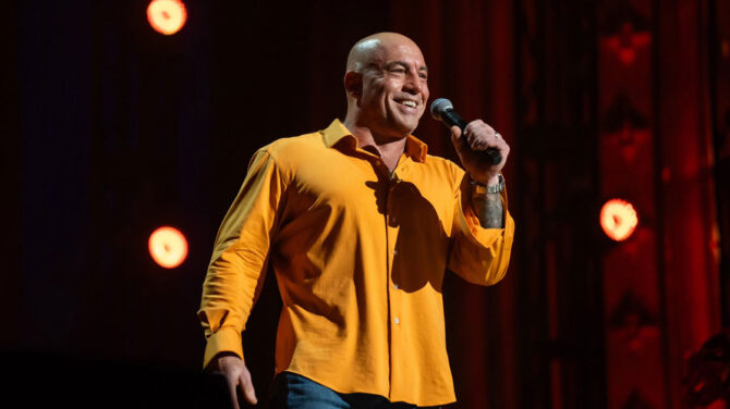 Joe Rogan performing stand-up comedy on stage during his "Burn the Boats" Netflix special.