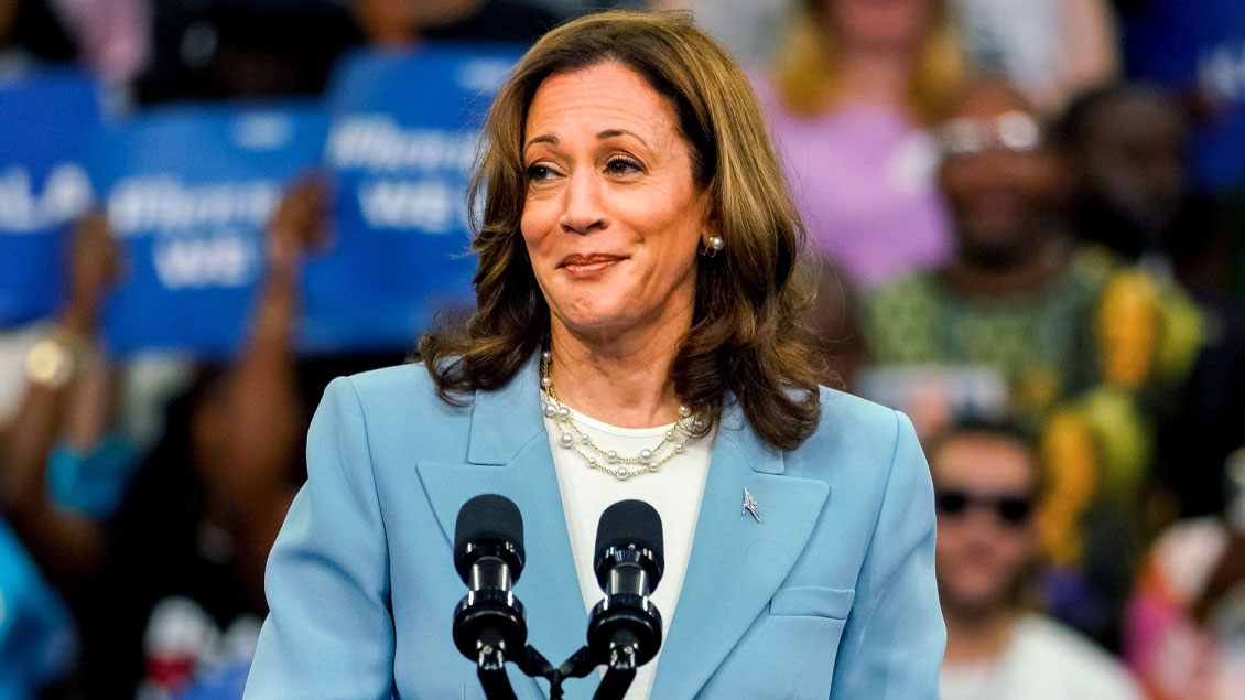Vice President Kamala Harris speaking at an event, with African Americans in the background.